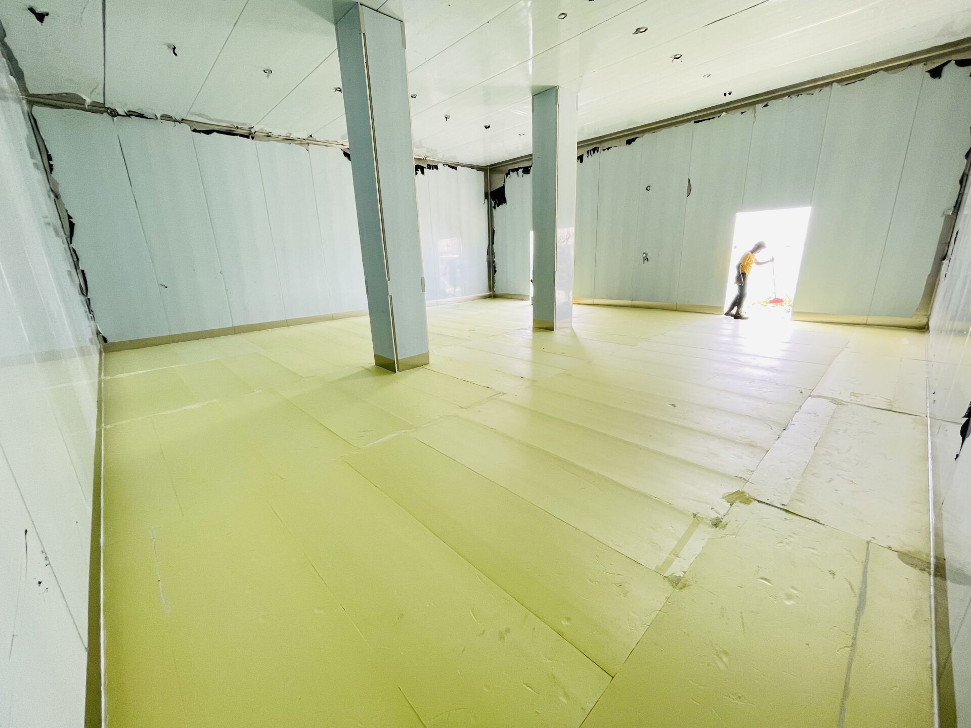 A man is standing in an empty room with a yellow floor.