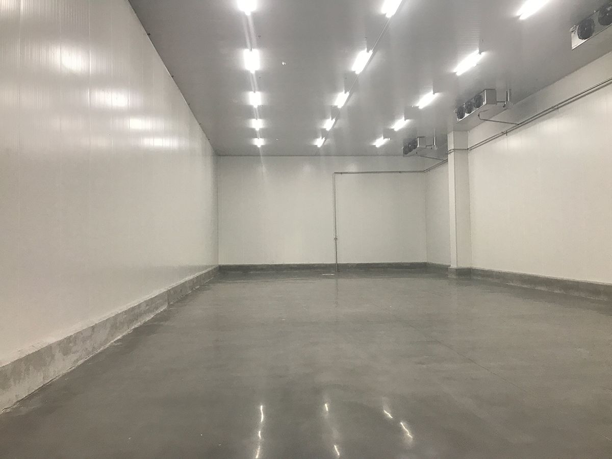 A large empty room with white walls and a concrete floor.