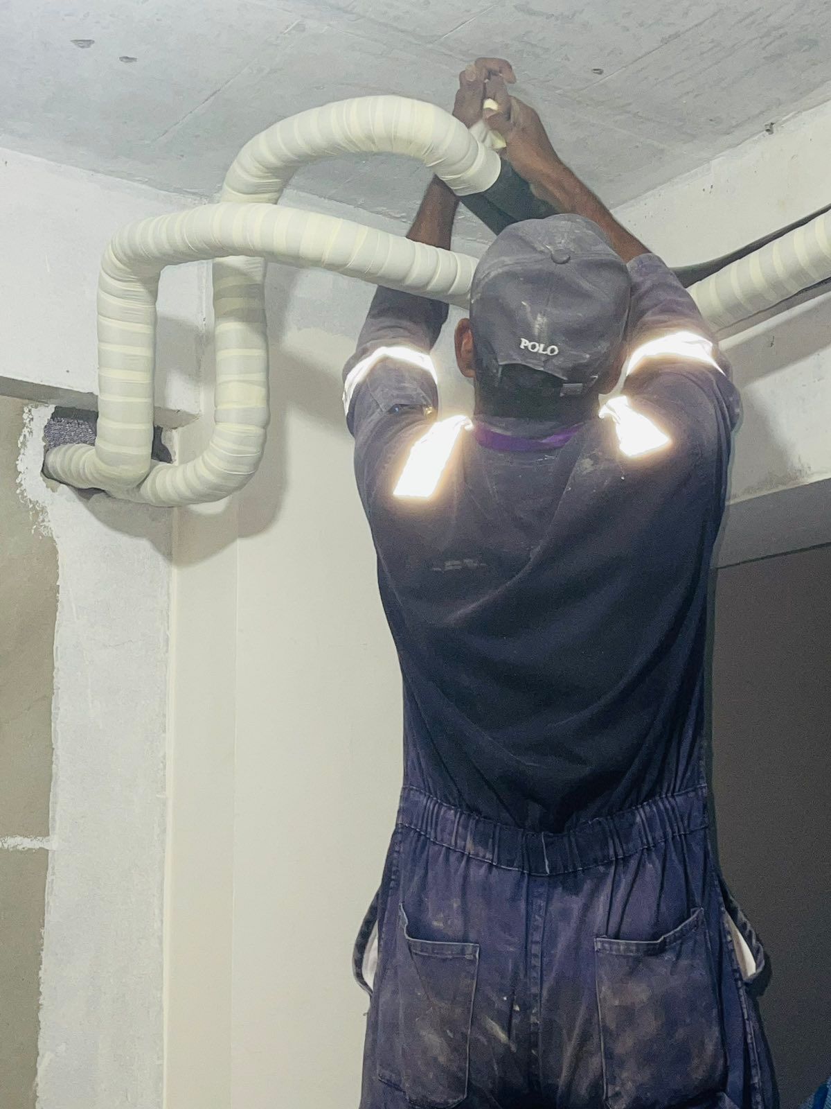 A man is working on a pipe on the ceiling.