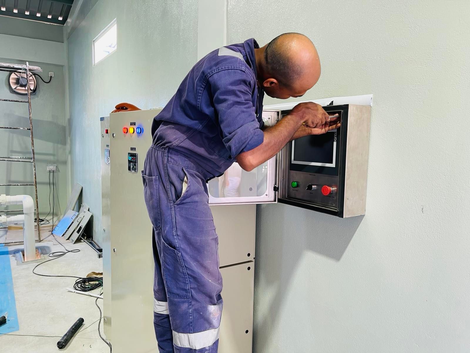 A man in a blue jumpsuit is working on a machine.