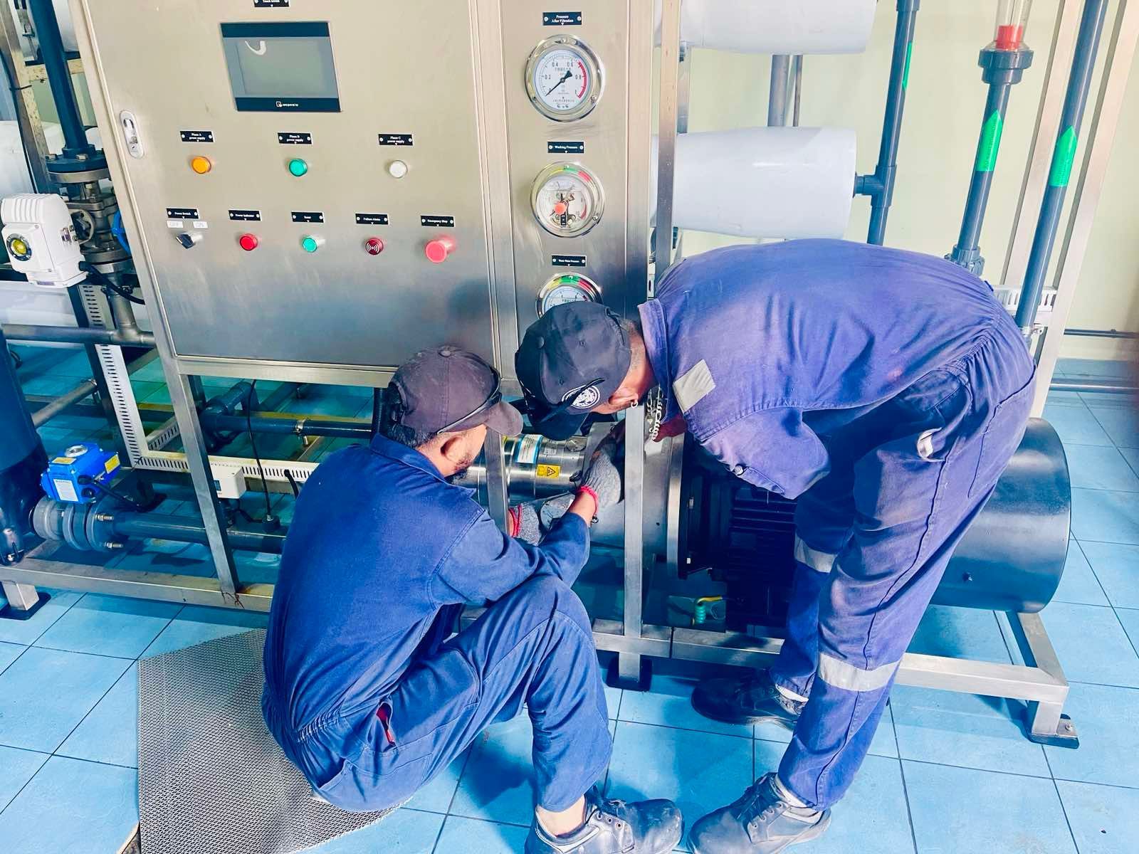 Two men are working on a machine in a factory.