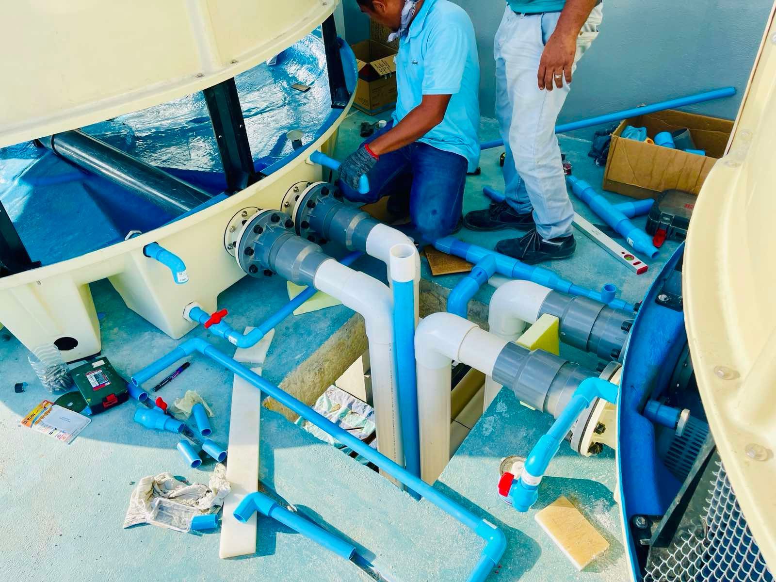 Two men are working on a water slide with blue pipes