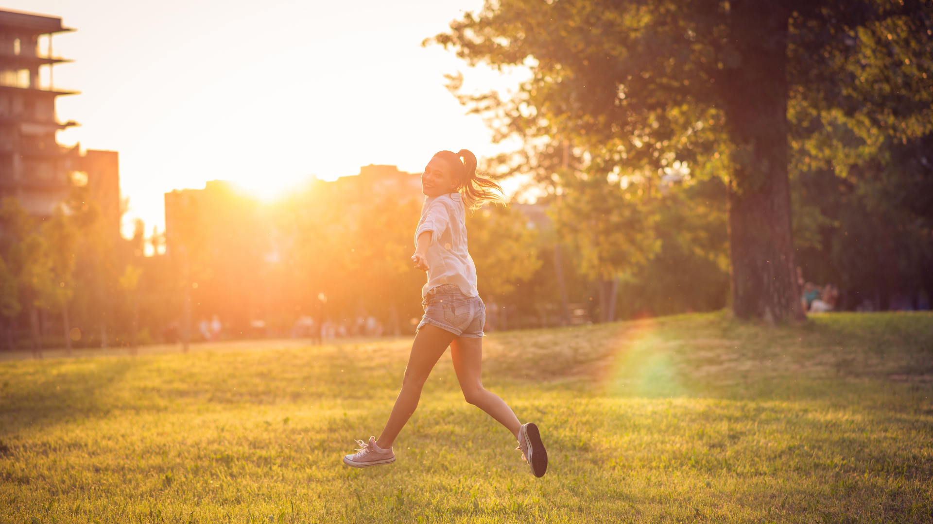 A woman is running in a park at sunset.