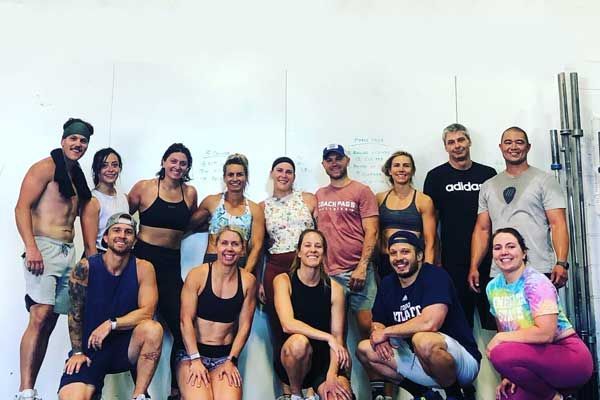 Group of people in fitness attire posing in the gym at South Tahoe CrossFit, some smiling.