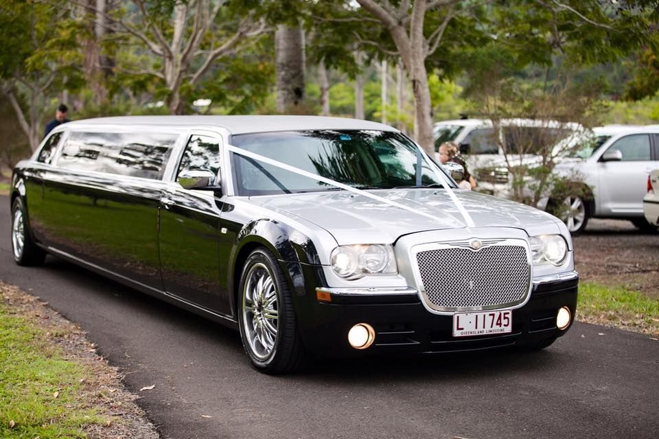 Black and silver limousine on a paved road, decorated with white ribbons; parked cars in the background. — Superstretch300 Limousines in Sunshine Coast, QLD