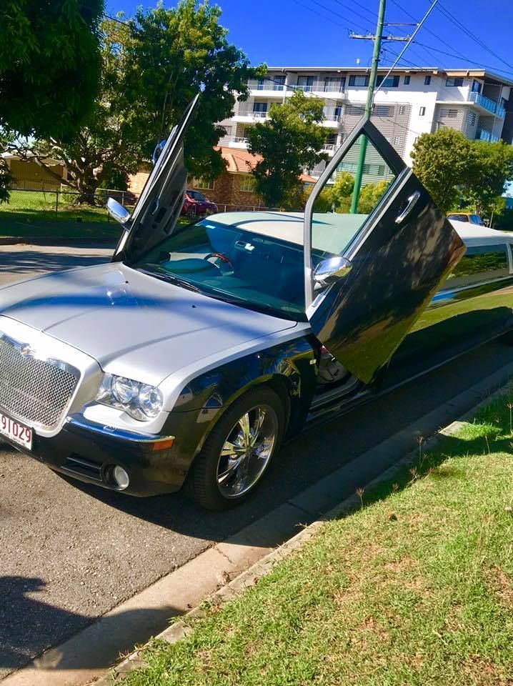 Black and silver Chrysler 300C limousine with gullwing doors open, parked on a street near grass and buildings. — Superstretch300 Limousines in Sunshine Coast, QLD