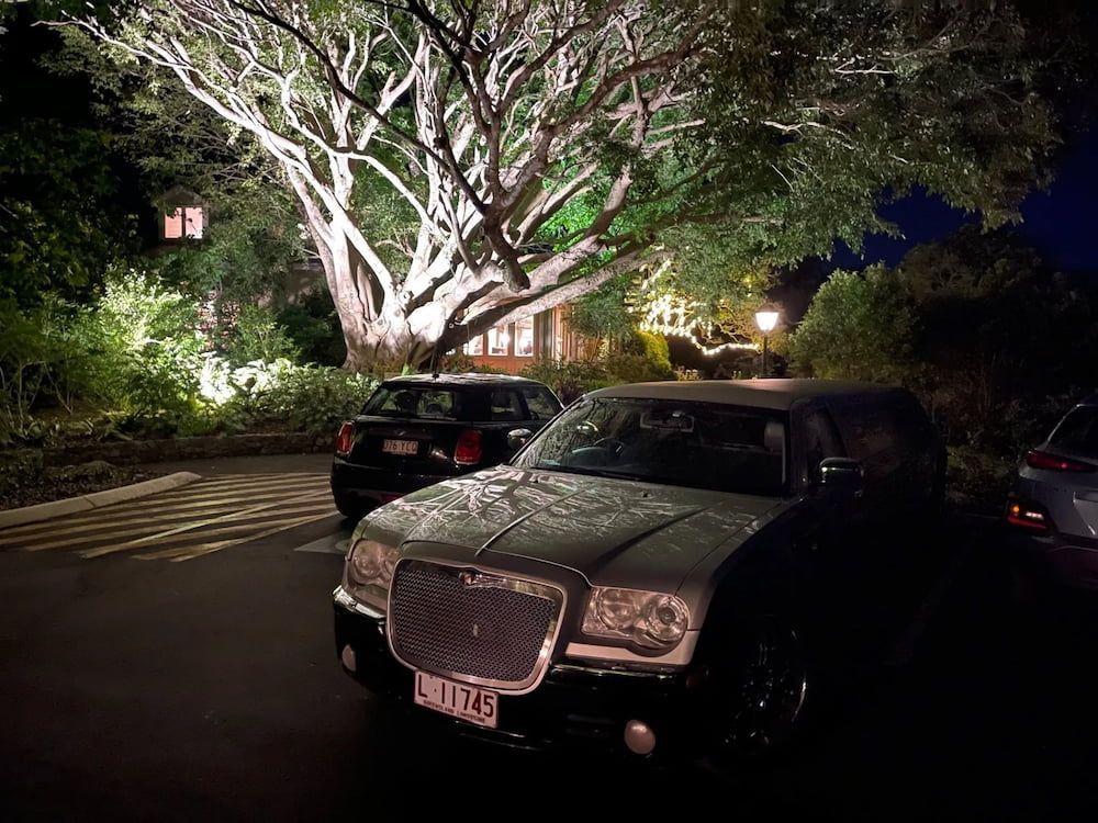 A White Car is Parked in a Parking Lot at Night — Superstretch300 Limousines in Sunshine Coast, QLD