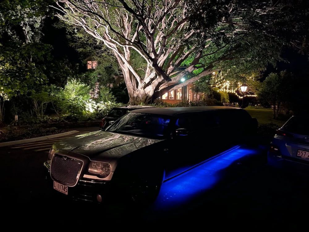 A Black Limousine is Parked in Front of a Tree at Night — Superstretch300 Limousines in Sunshine Coast, QLD