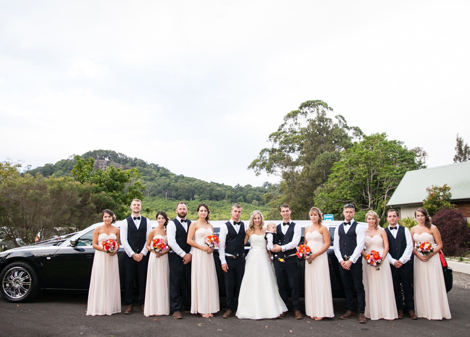 Wedding Party Posing With a Black Limousine — Superstretch300 Limousines in Sunshine Coast, QLD