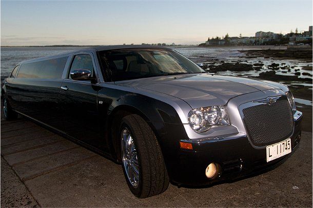 A Black Limousine is Parked Next to a Body of Water — Superstretch300 Limousines in Sunshine Coast, QLD