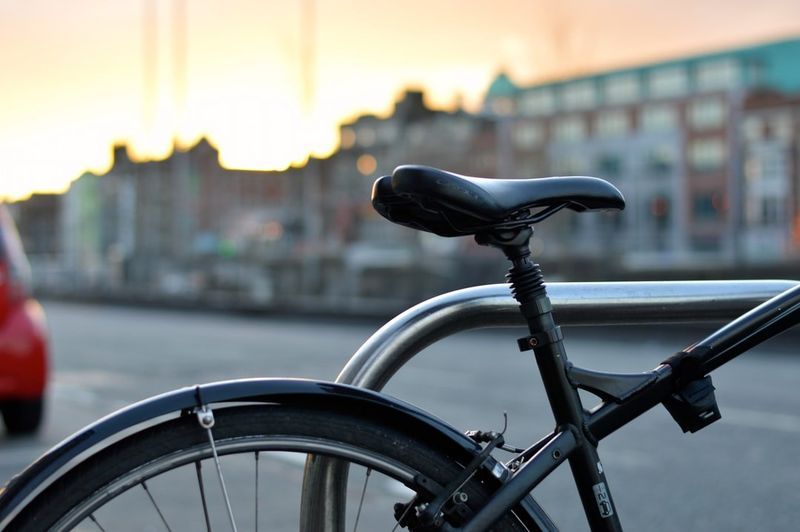 A bicycle is locked to a railing on the side of the road.