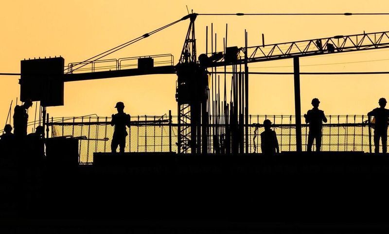 A group of construction workers are standing on top of a building under construction.