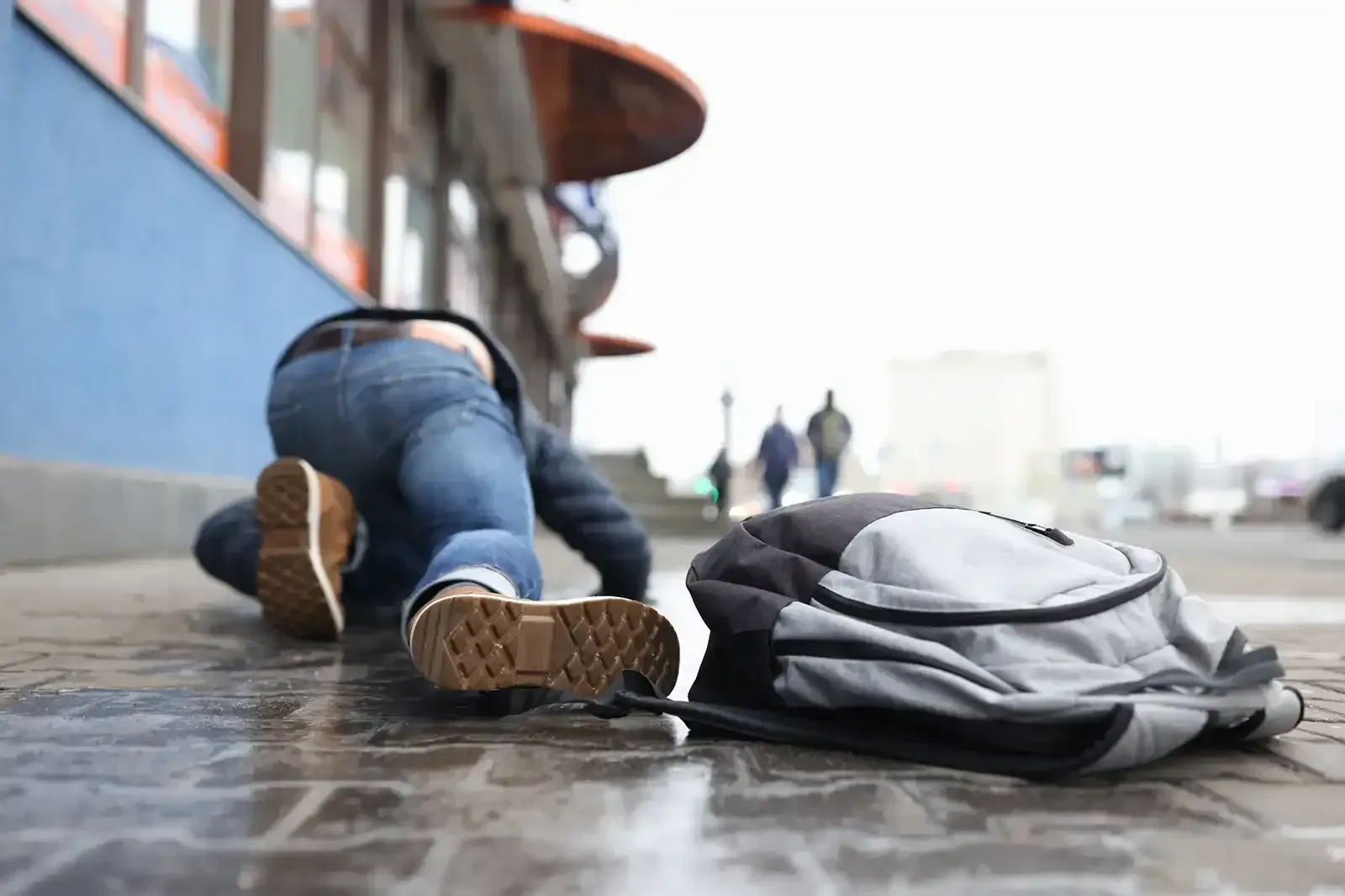 A person is laying on the ground next to a backpack.