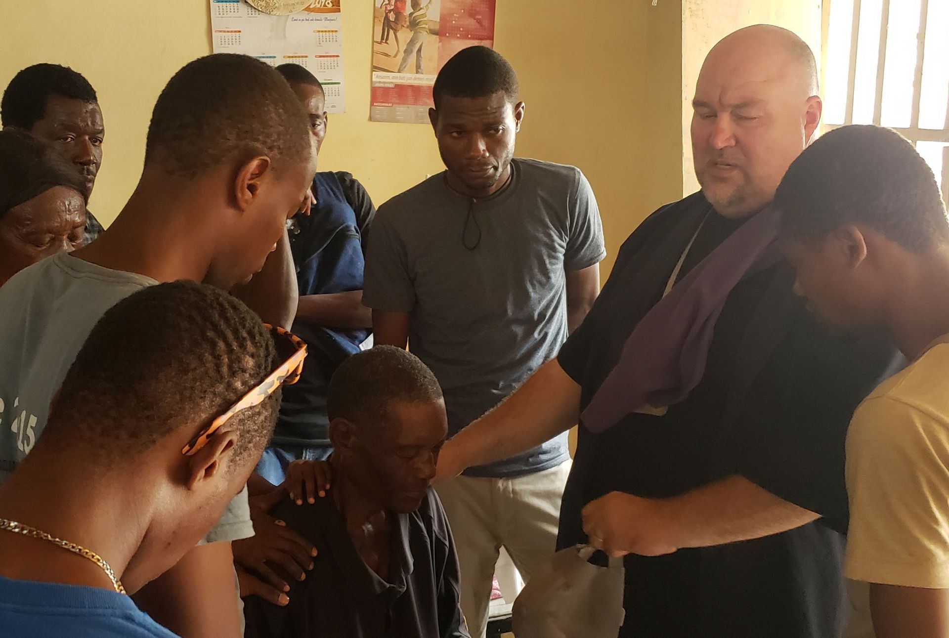 Pastor Jeremy prays for a man who asked to receive Christ. He sits between a circle of brothers in Haiti,