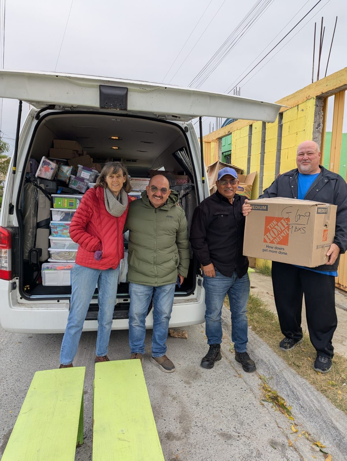 Boxes in a trailer being loaded by several people standing near stairs.