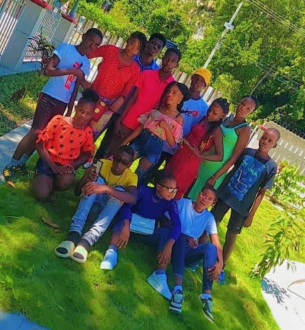 Group of young people posing on grass. Bright clothing, outdoors, smiling.