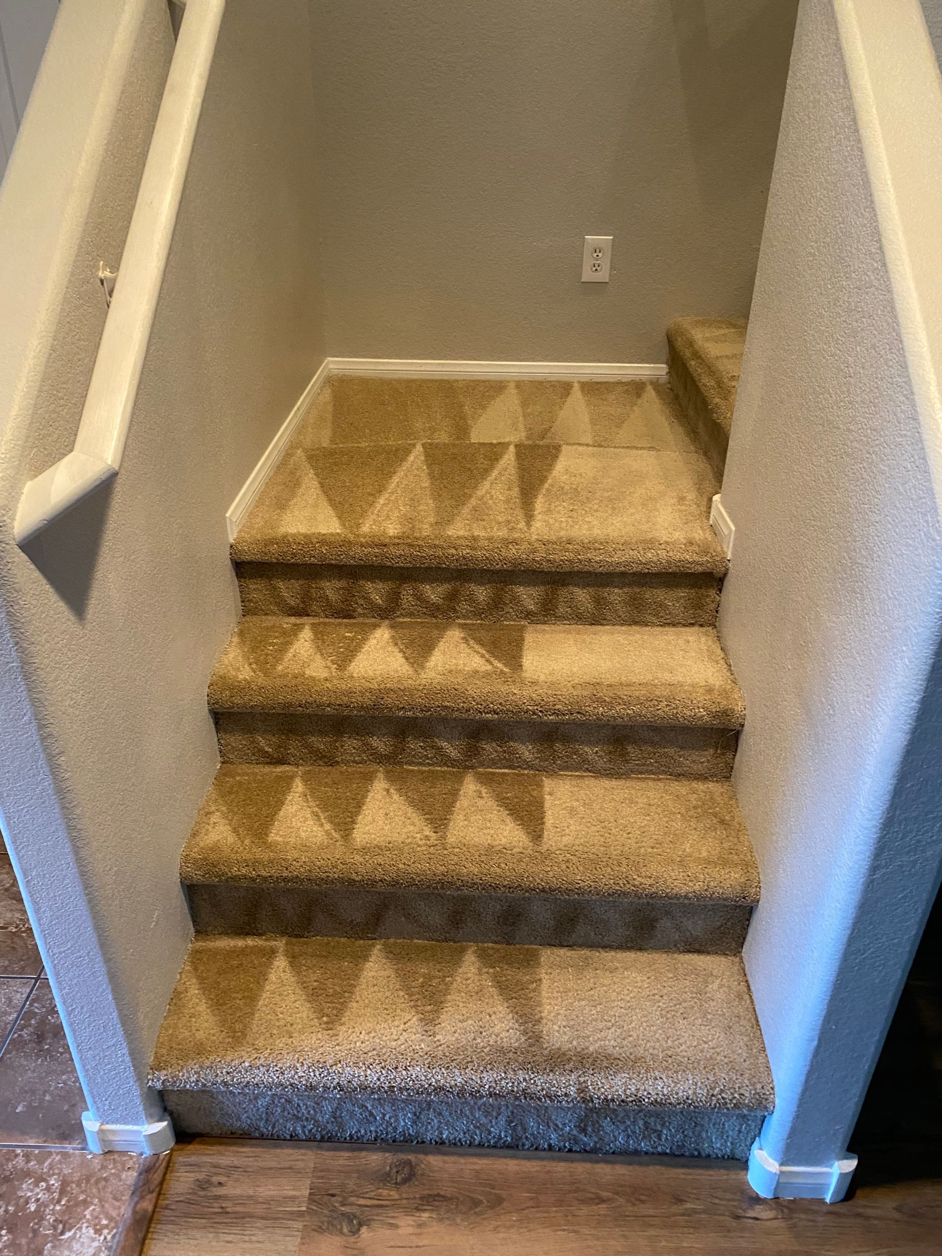 A set of stairs with a pattern on the carpet.