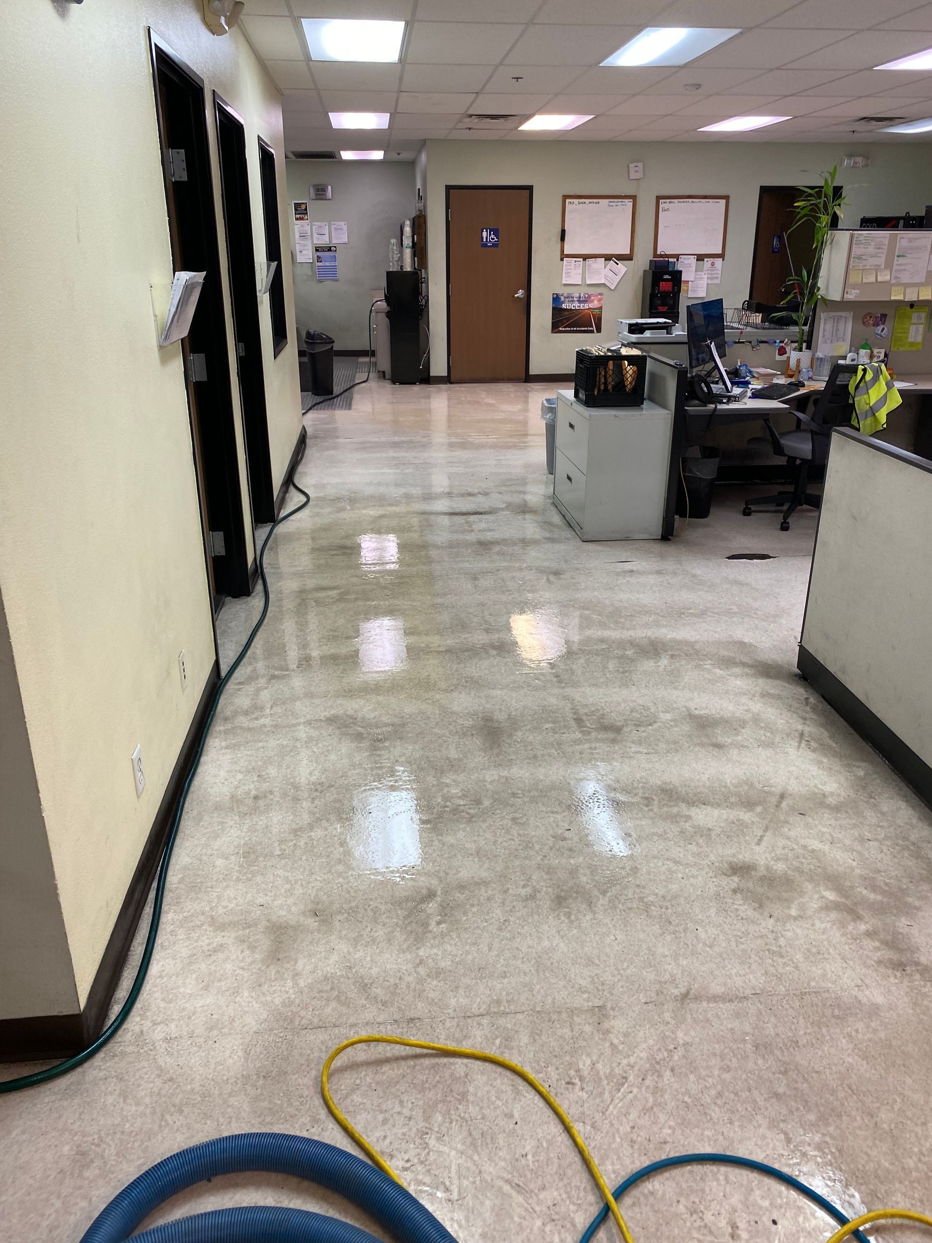 A hallway in an office with a vacuum on the floor