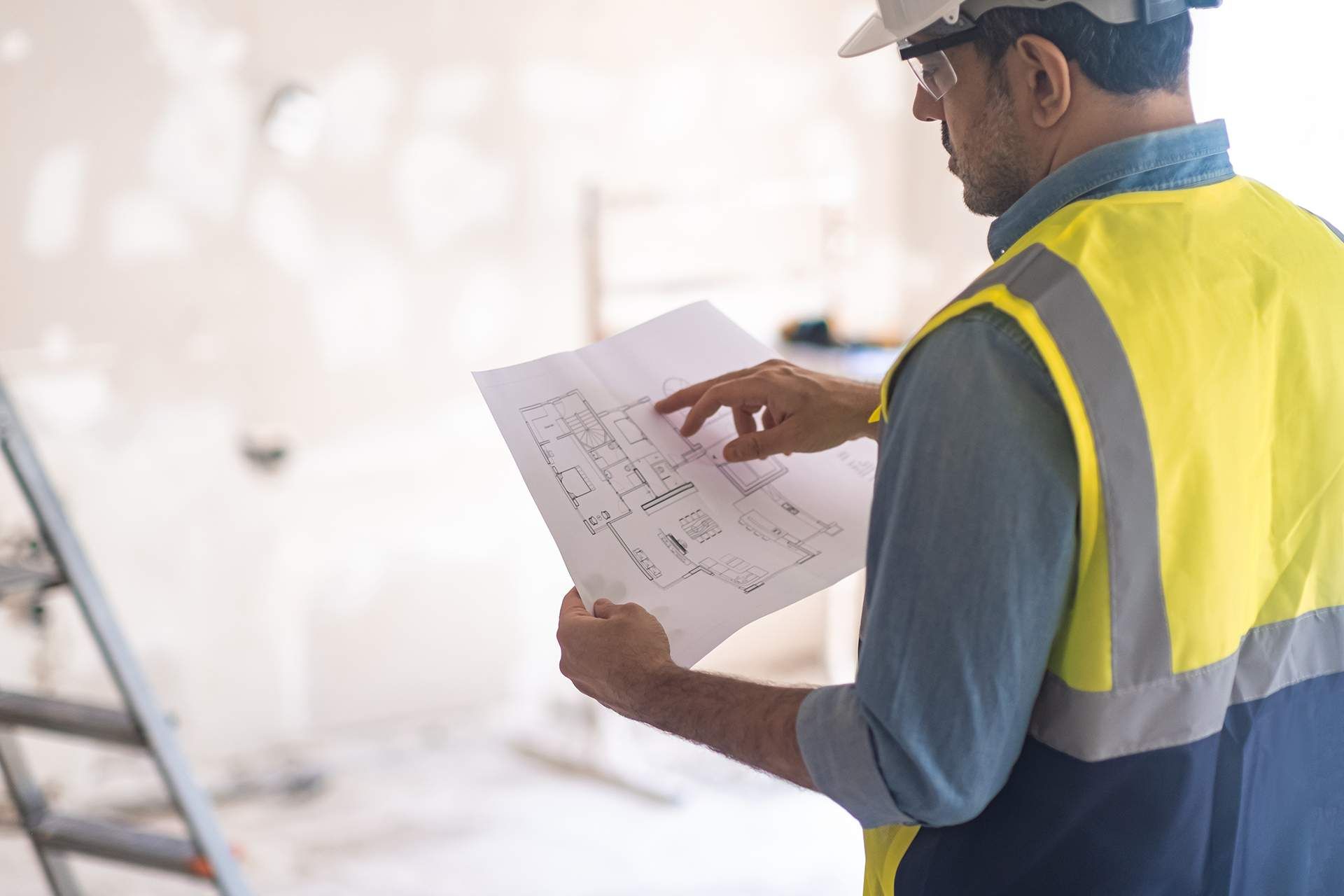 Man in vest checking apartment drawing paper before starting renovation process specialist in uniform