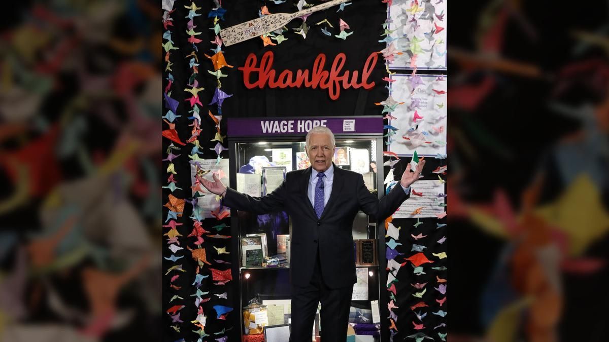 Alex Trebec standing among 1,000 cranes created by PCS students