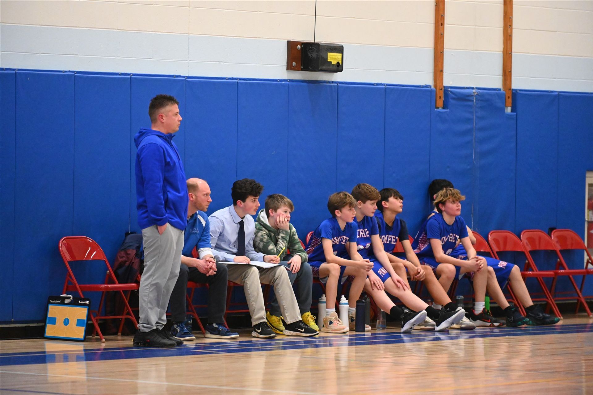 some of the 2023-24 boys basketball team and their coaches sitting on the 
sidelines