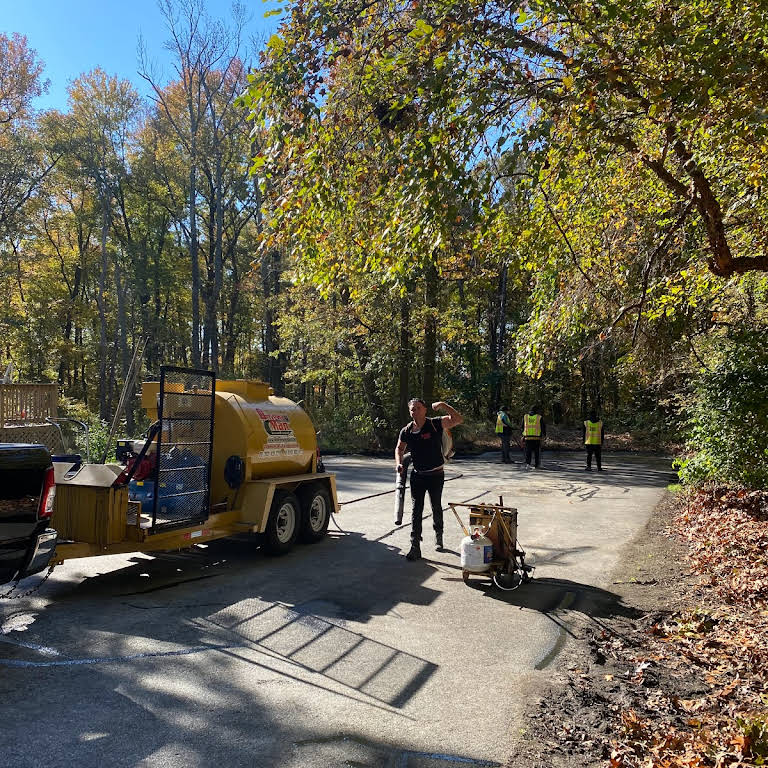 A man is standing in front of a tanker truck on a road.