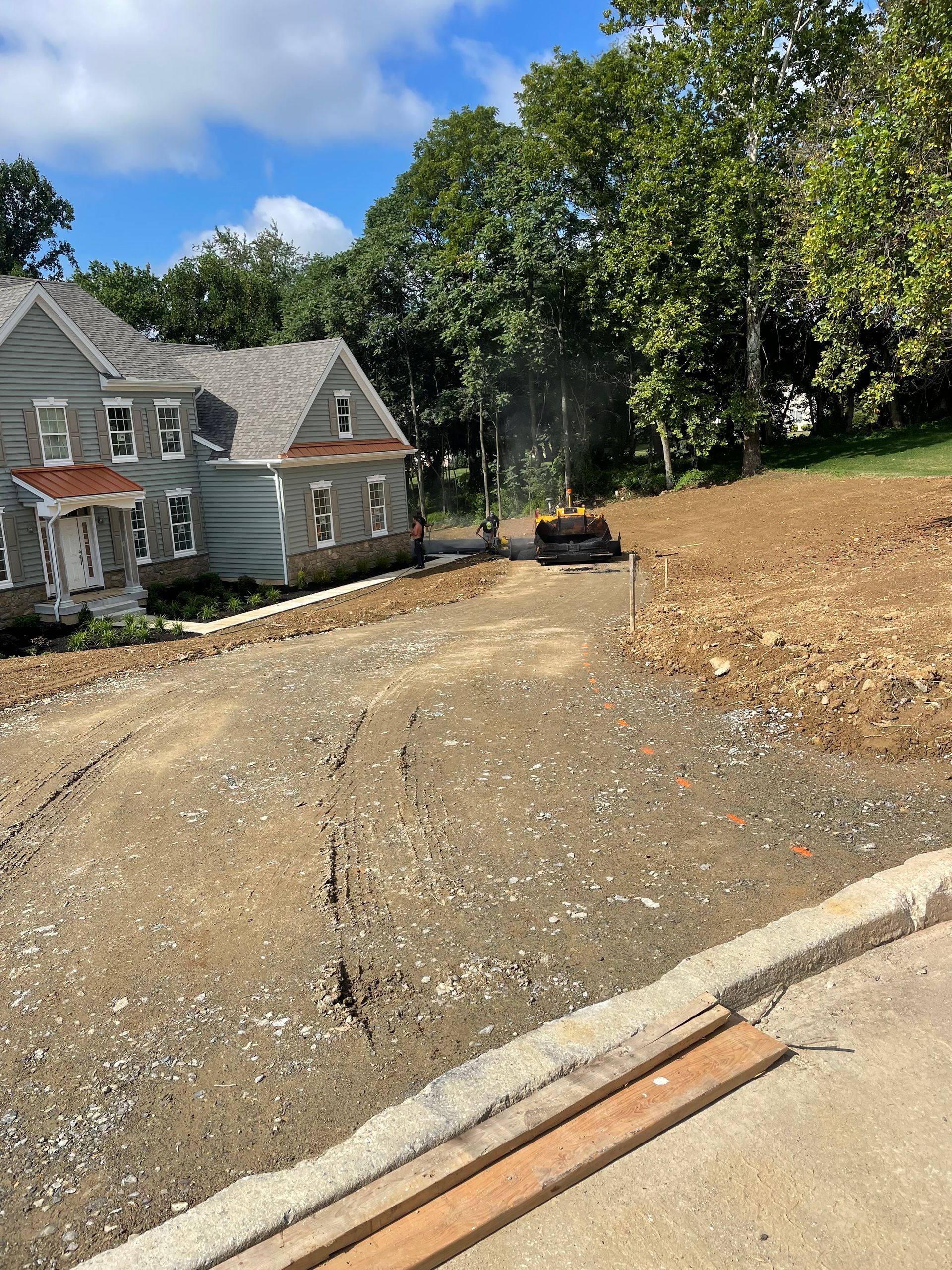 A house is sitting on top of a dirt hill next to a road.