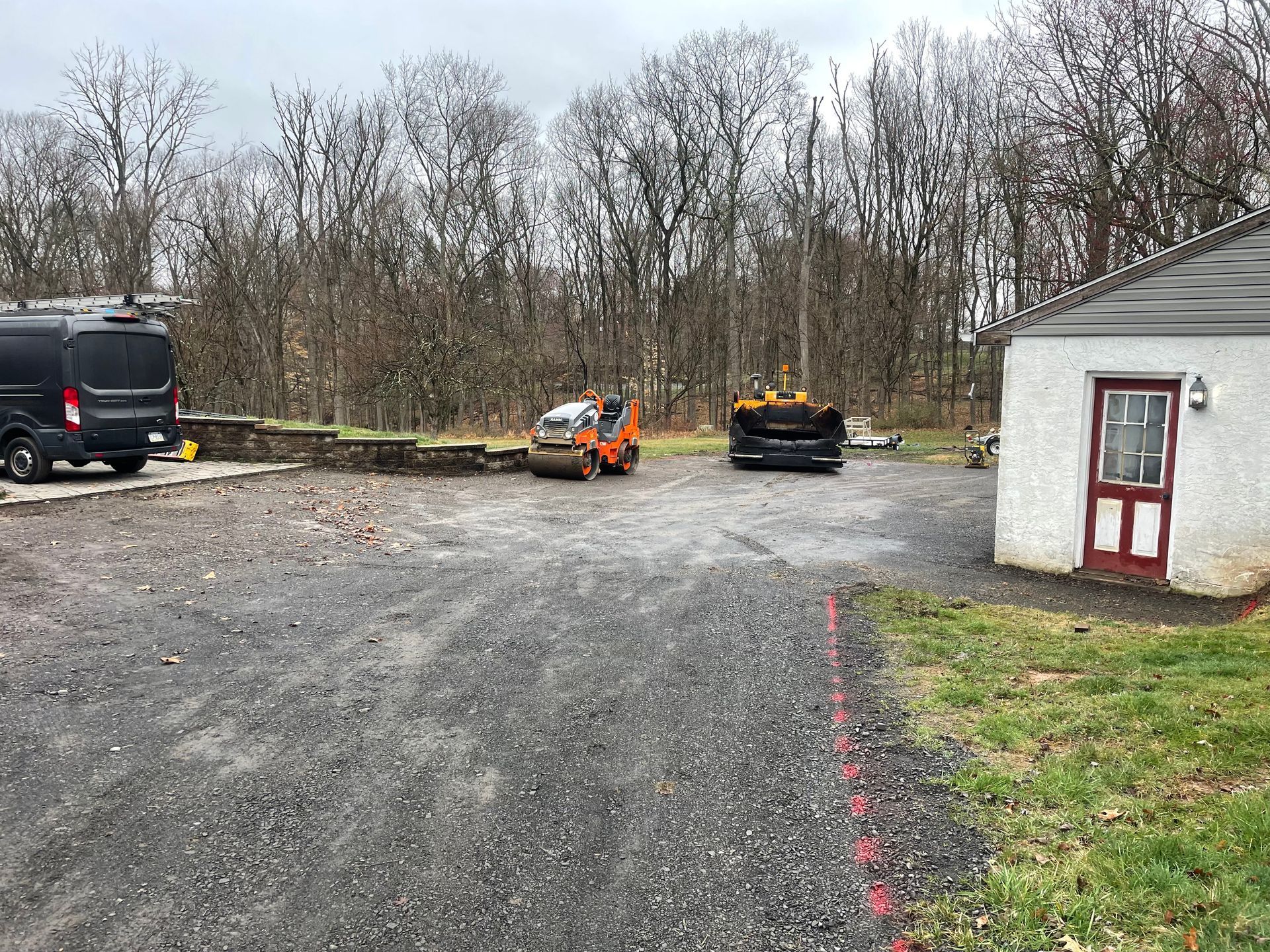 A black van is parked in a parking lot next to a white building.