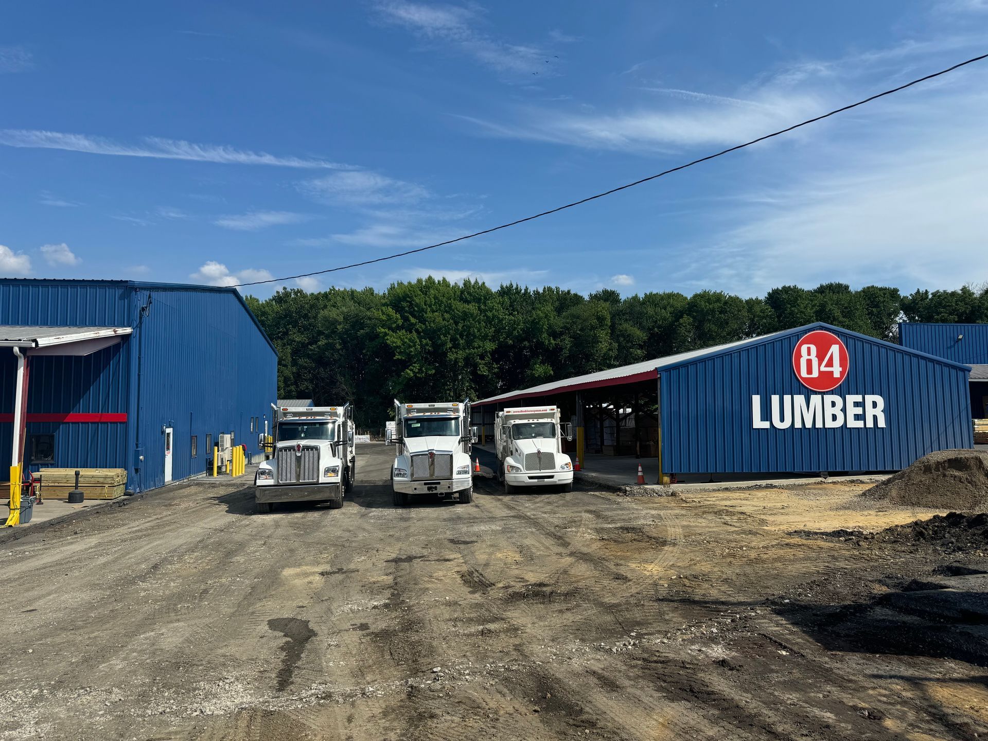 Three trucks are parked in front of a building that says b4 lumber.