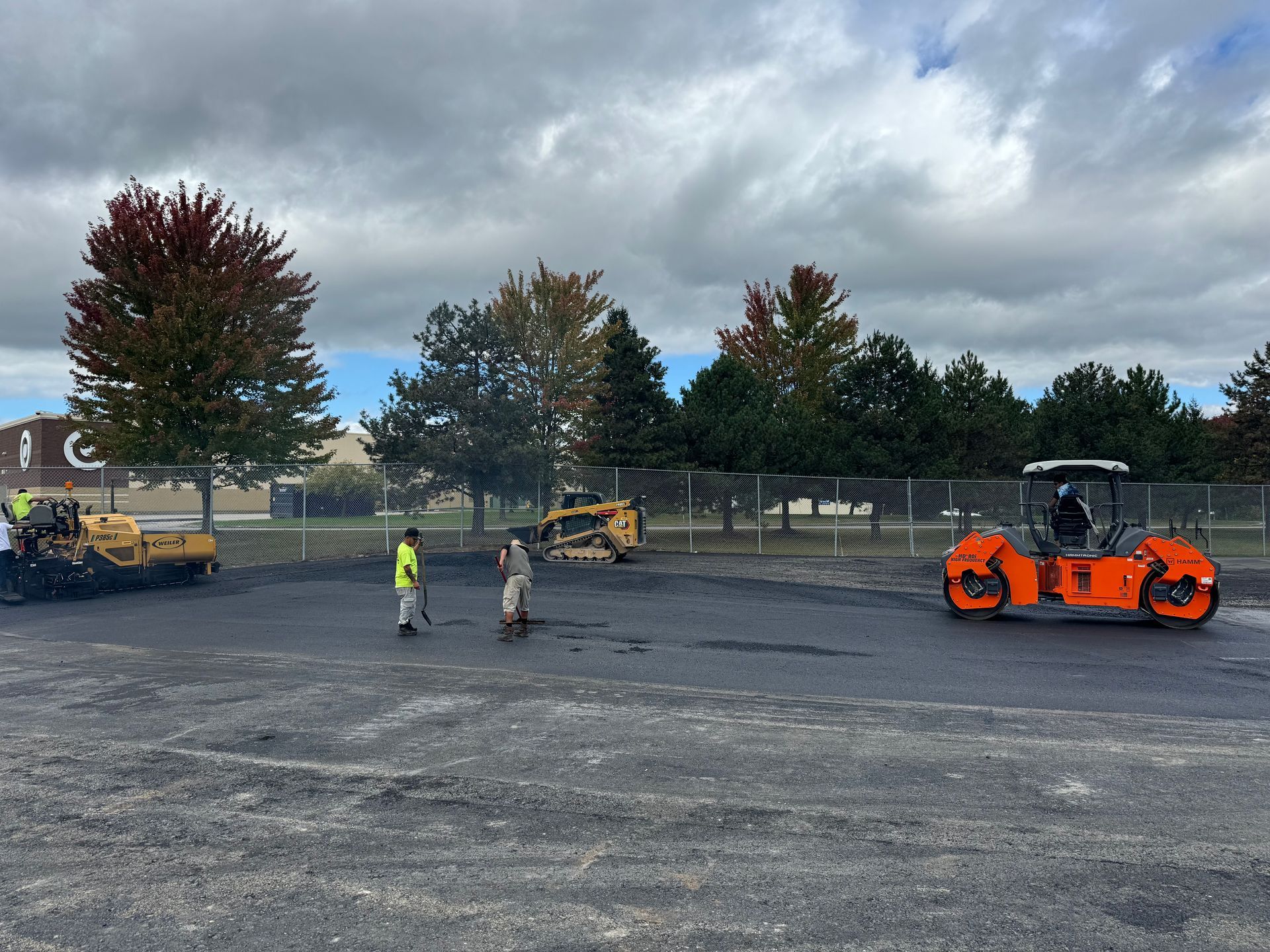 A group of construction workers are working on a parking lot.
