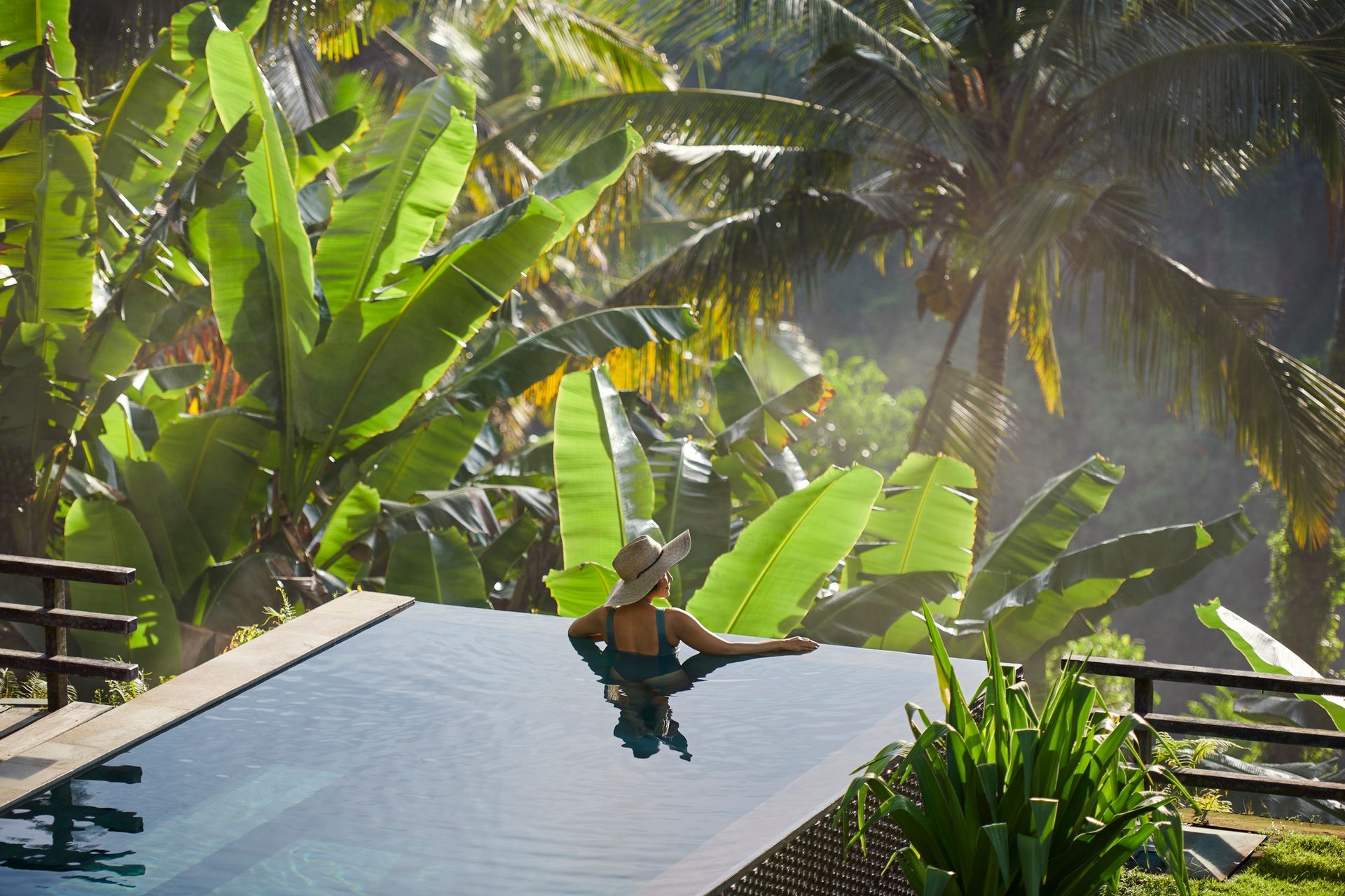 Woman inside a hot tub in a tropical hotel looking at tropical plants.