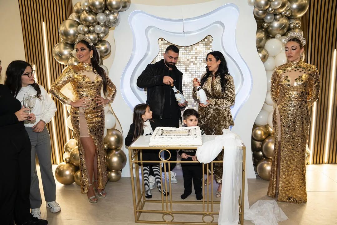 Una composizione di palloncini bianchi con luci e orsacchiotti allestita accanto a una piscina sotto una palma.