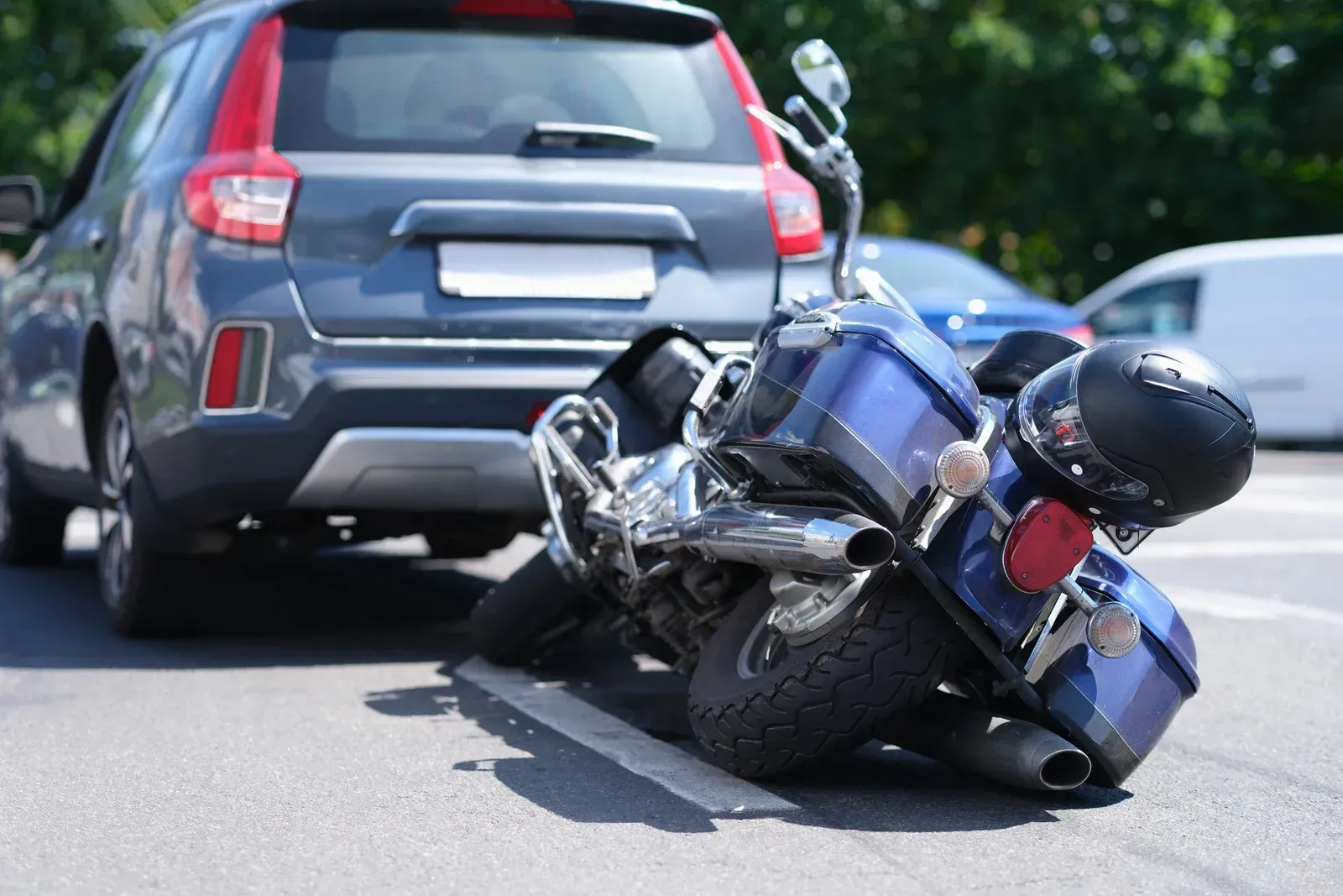 Car crashed into motorcycle on a road, blue vehicle and motorcycle on the asphalt, accident scene.