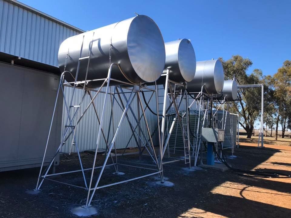 A Row of Stainless Steel Tanks Are Sitting in Front of A Building — Andrew Klein Painting in Toowoomba, QLD