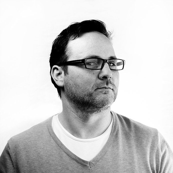 A black and white photo of a man wearing glasses and a sweater.