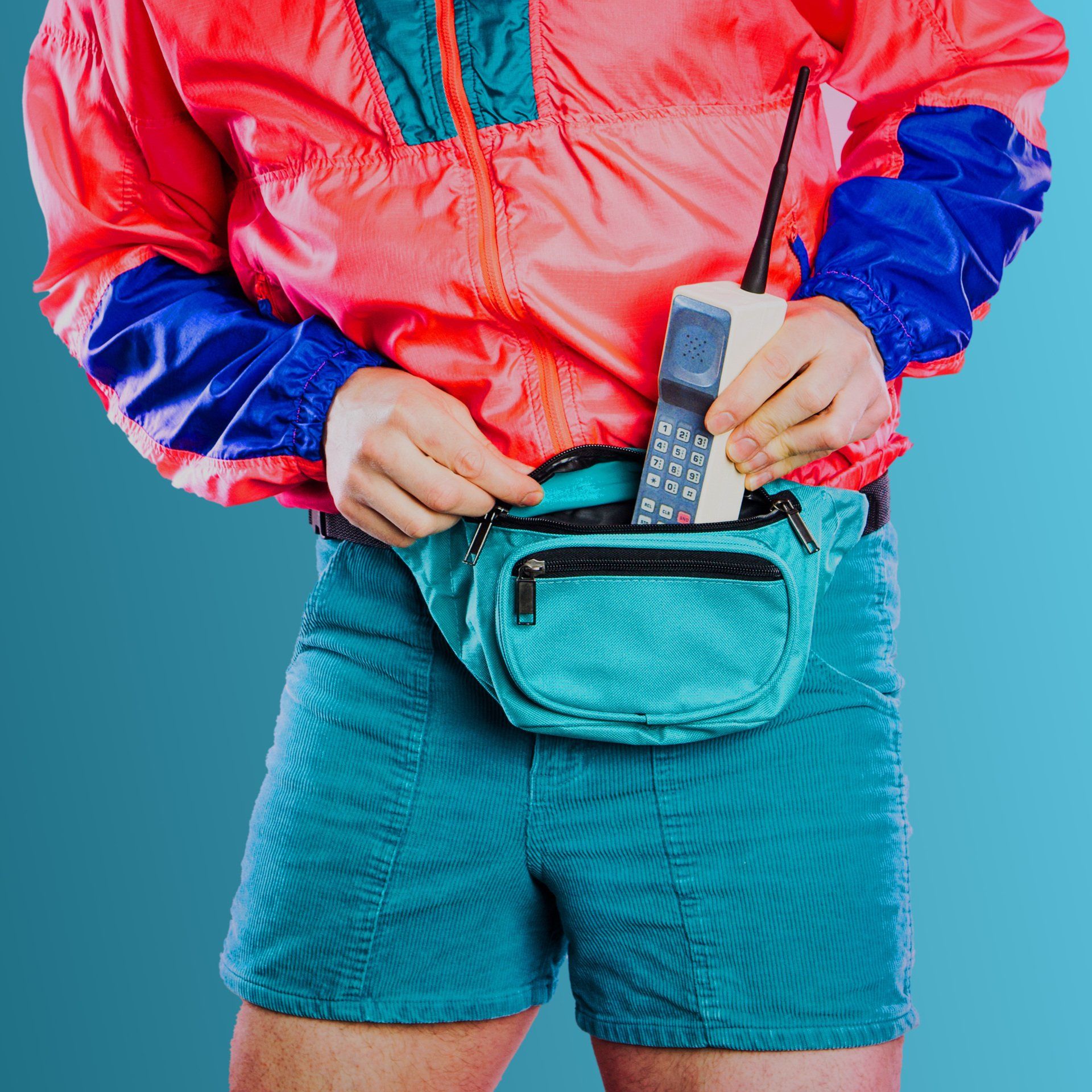 A photo of a fanny pack and a brick cell phone.