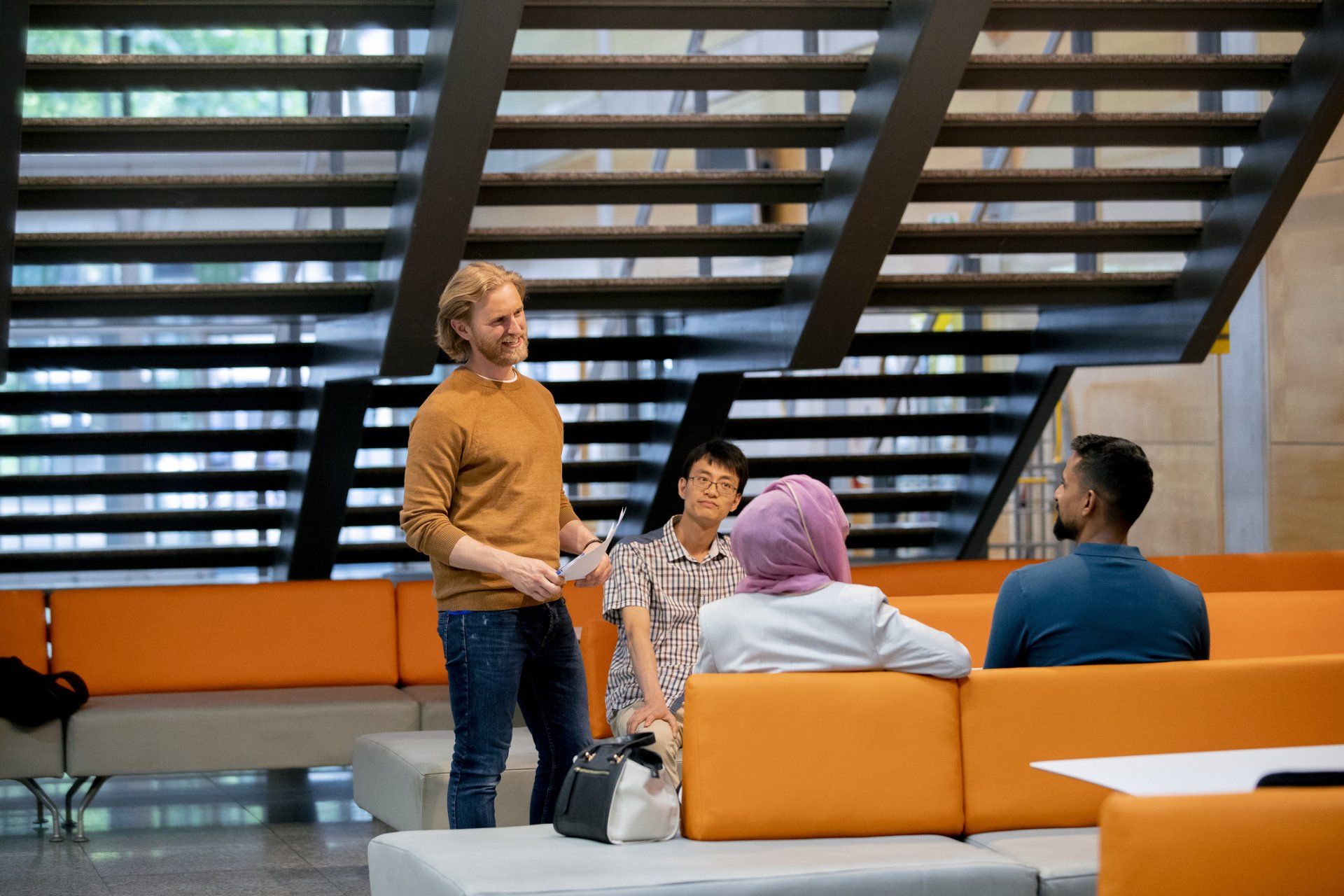 A man is standing in front of a group of people sitting on a couch.