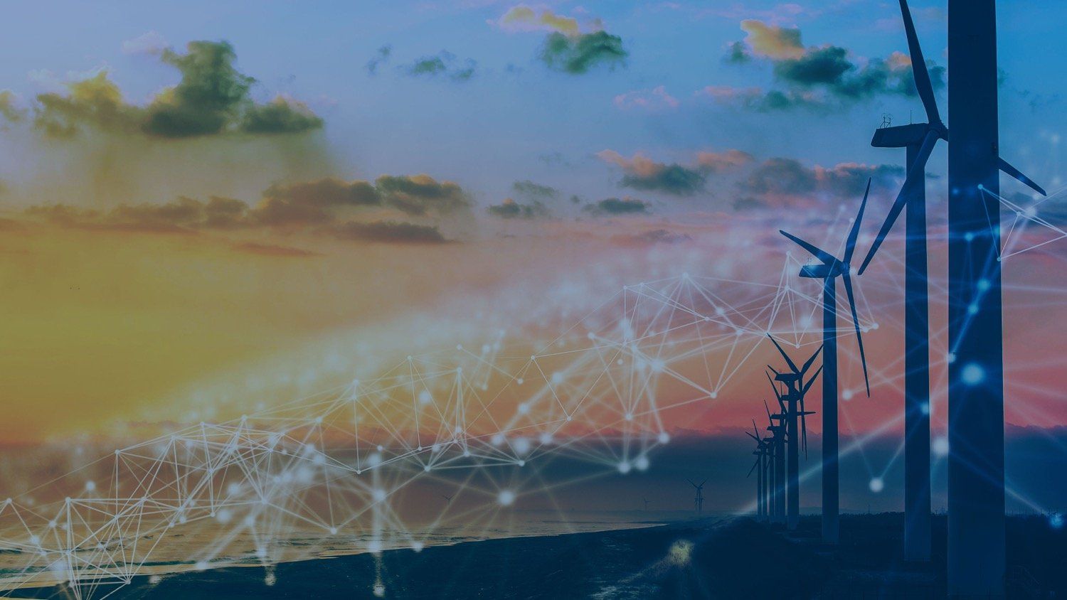 A row of wind turbines in a field with a sunset in the background.