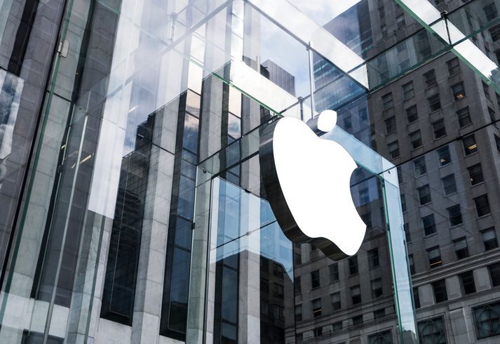 An apple logo is reflected in a glass building