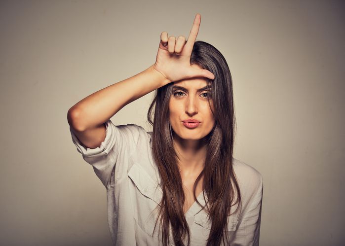 A woman is making a funny face with her hand on her forehead.