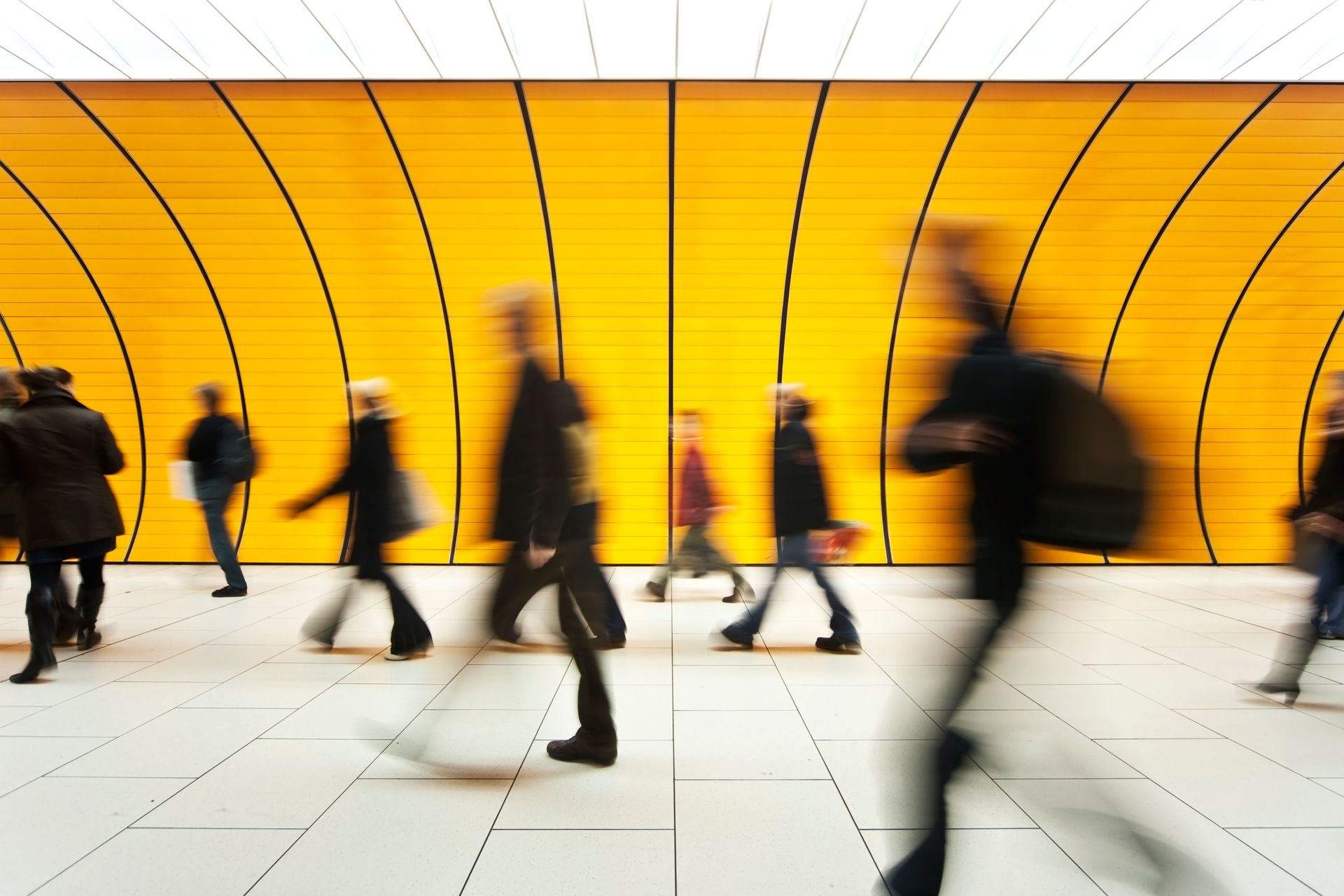 A blurry picture of people walking in front of a yellow wall