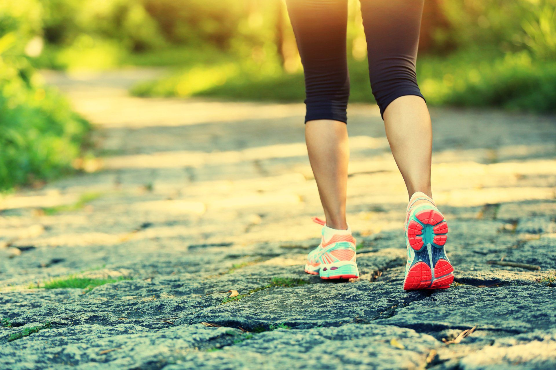 A woman is walking on a stone path in a park.