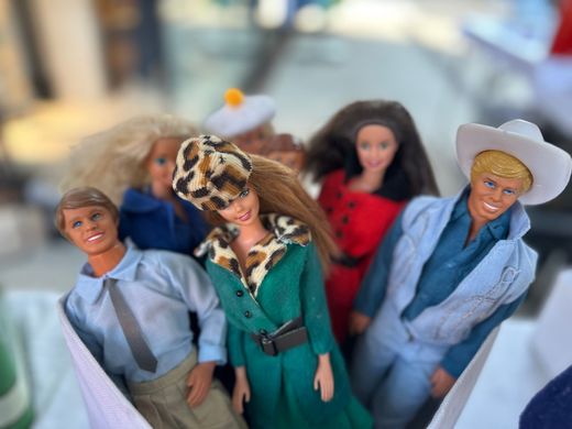 Miniatur-Modepuppen in farbenfrohen Outfits posierten gemeinsam auf einer hellen Oberfläche.