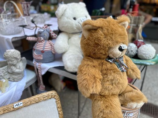 Stoffteddybären, die an einem Marktstand ausgestellt sind, darunter ein hellbrauner Bär im Vordergrund und ein weißer Bär dahinter.