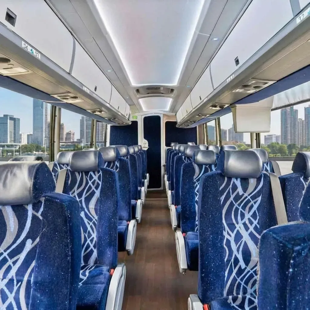 Interior of a blue passenger bus with rows of seats, overhead storage, and city views through the windows.