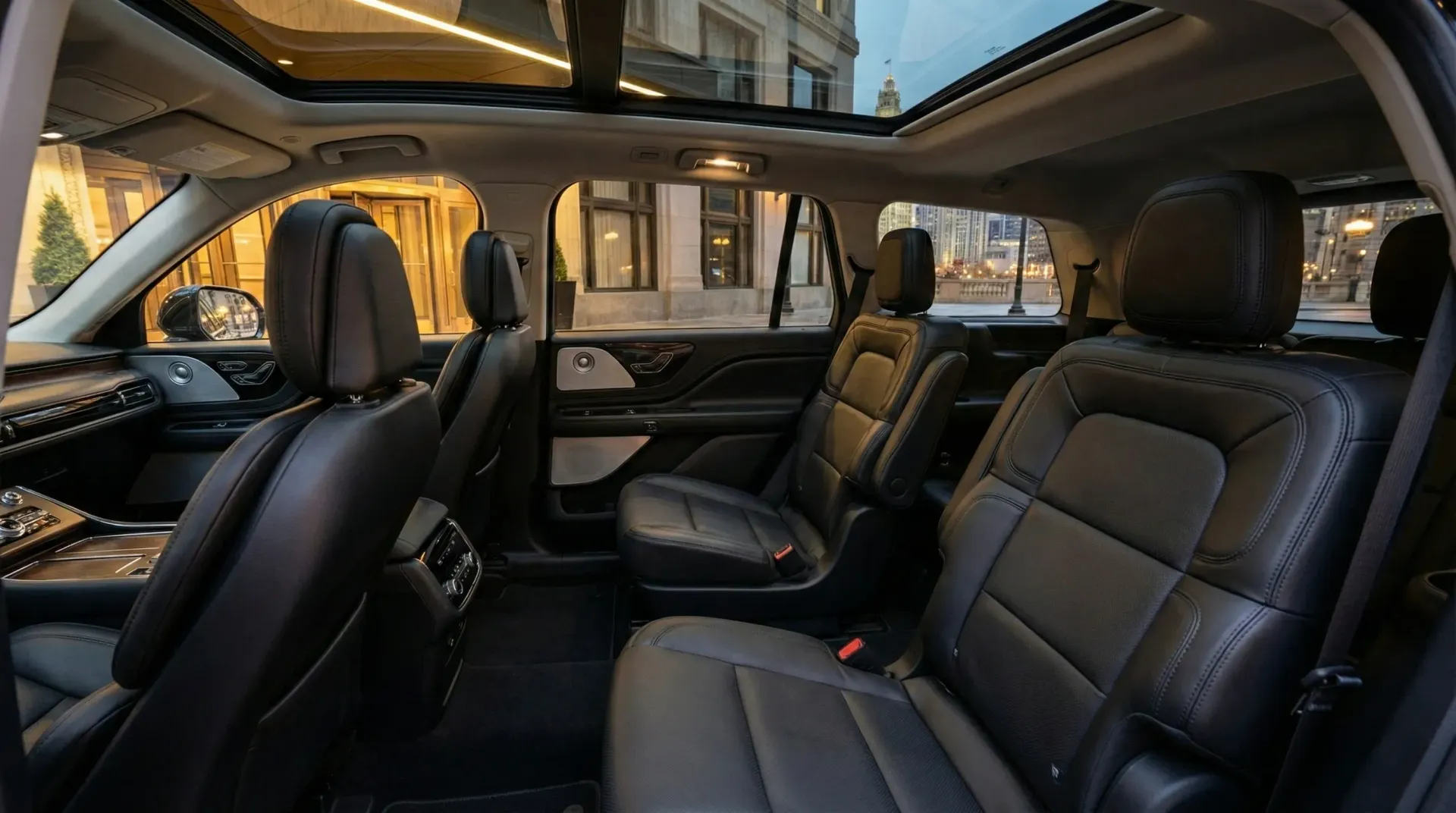 Interior of a black leather SUV with three rows of seats and a panoramic sunroof.