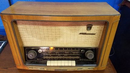 An old radio is sitting on a wooden table.