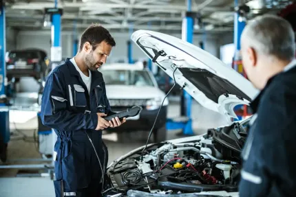 Two mechanics are working on a car in a garage.