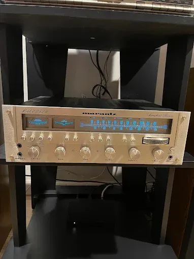 A marantz stereo receiver is sitting on top of a black shelf.