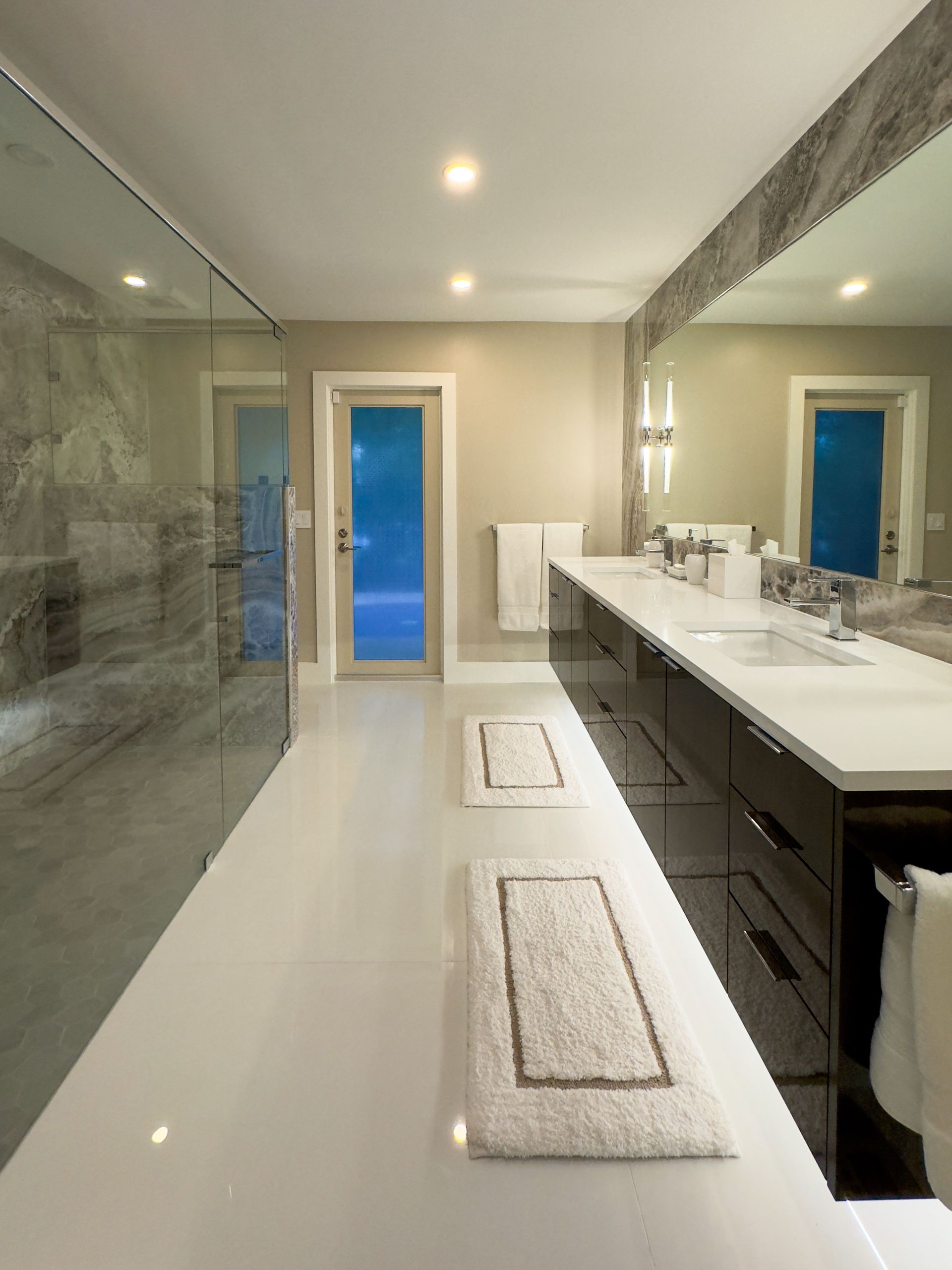 A primary bathroom with a double vanity, large mirror, and walk in shower. 